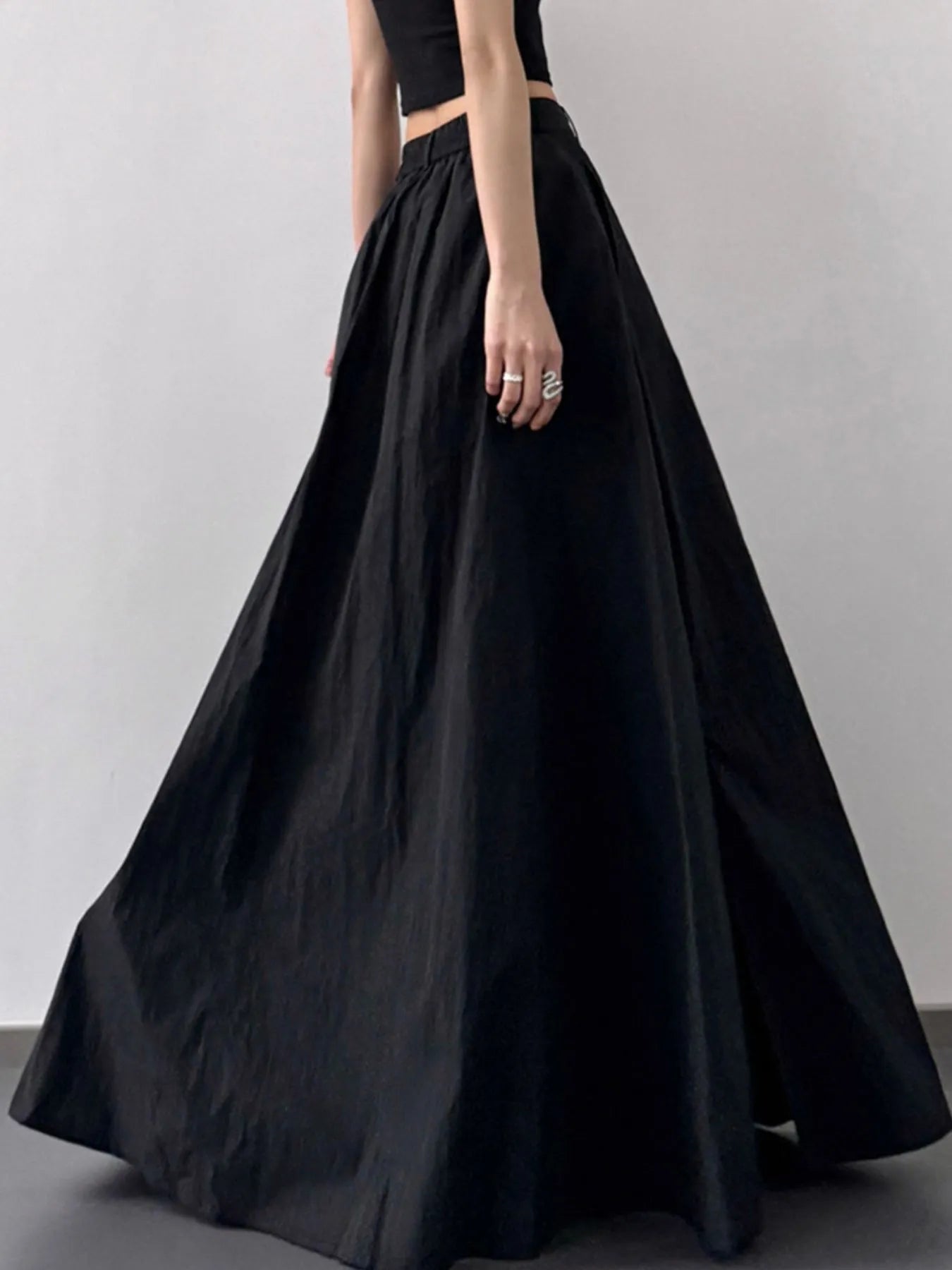 Black skirt worn by a person on a plain background