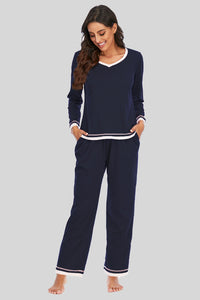 Woman wearing navy blue pajamas with white trim on a gray background