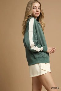 Woman wearing a green and white sweatshirt with a beige background