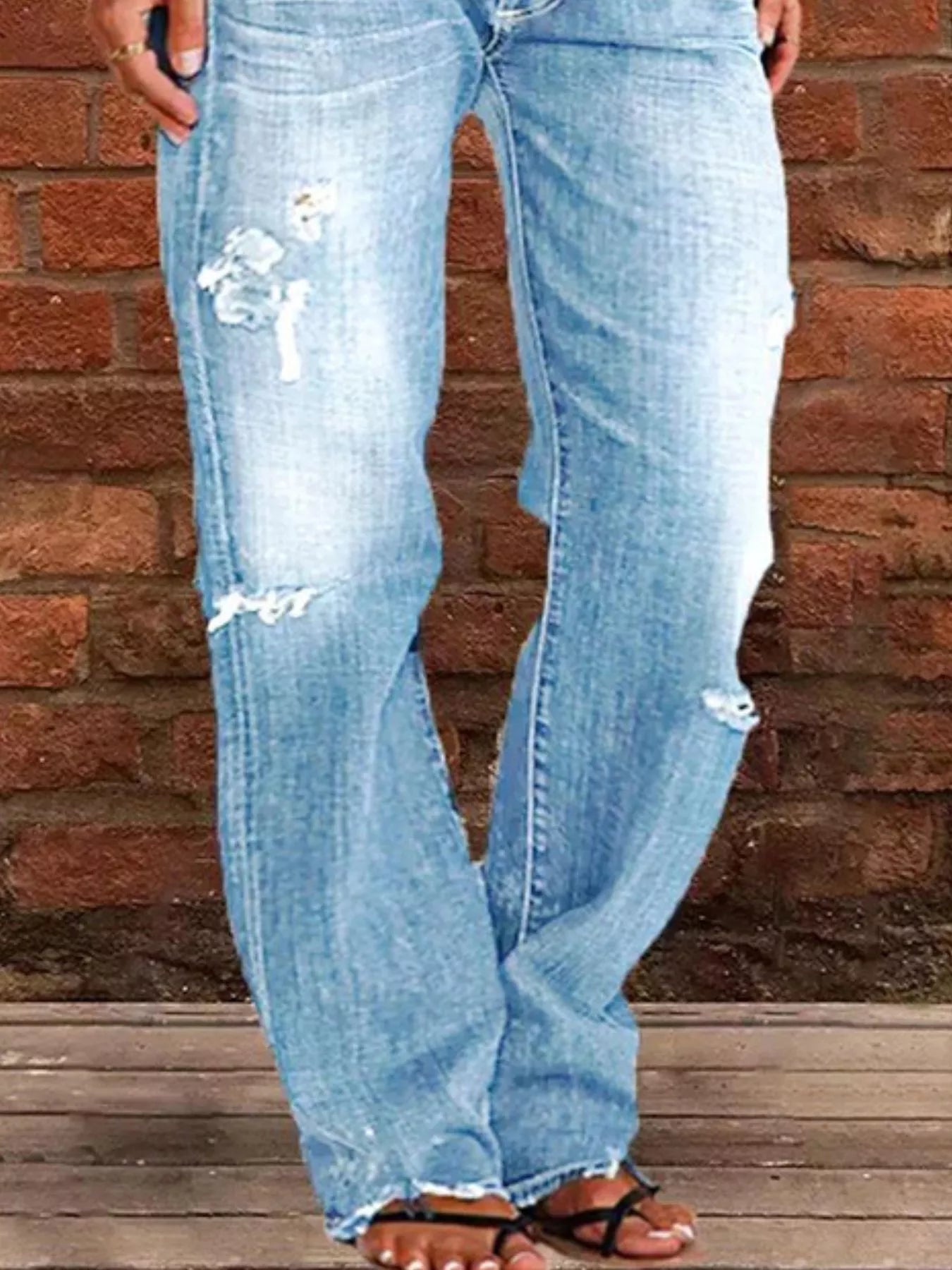 Light blue jeans with floral designs on a brick wall background