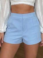 Light blue shorts worn by a person with a white lace top and sheer white cardigan.