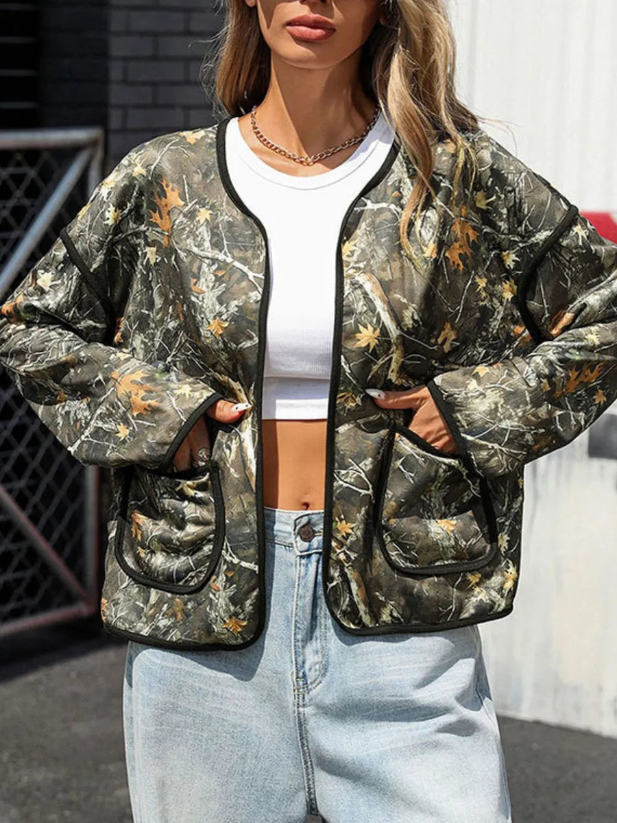 Person wearing a camouflage jacket with a white top and light blue jeans outdoors.