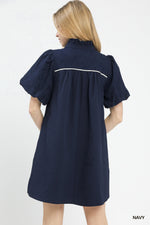 Woman wearing a navy dress with white trim on a white background