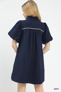 Woman wearing a navy dress with white trim on a white background