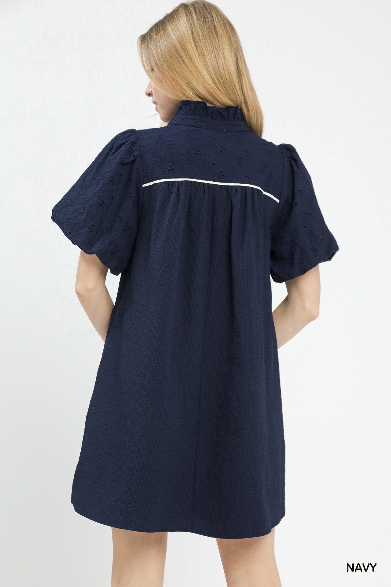 Woman wearing a navy dress with white trim on a white background