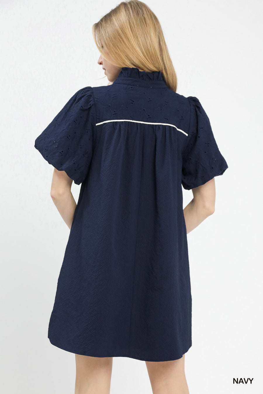 Woman wearing a navy dress with white trim on a white background