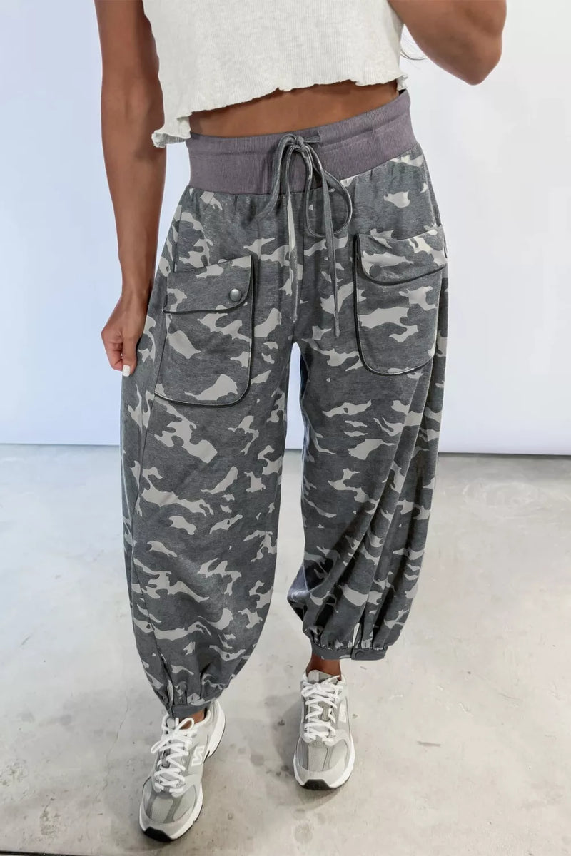 Camouflage pants worn by a person on a plain background