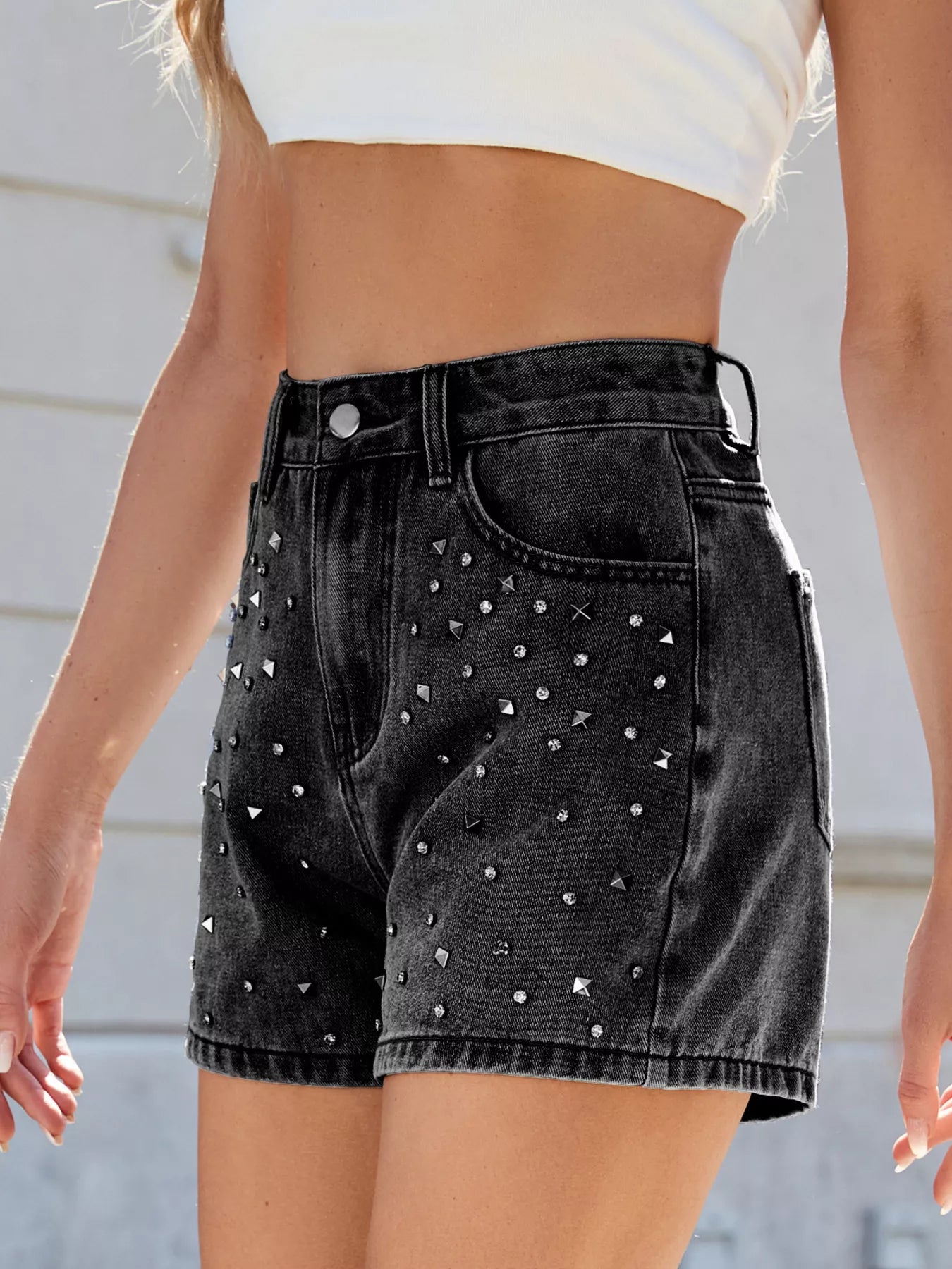 Black denim shorts with silver studs worn by a person against a neutral background