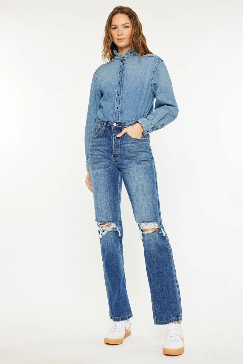 Woman wearing a denim outfit with ripped jeans on a white background