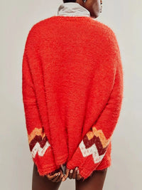 Red sweater with patterned cuffs worn by a person on a plain background