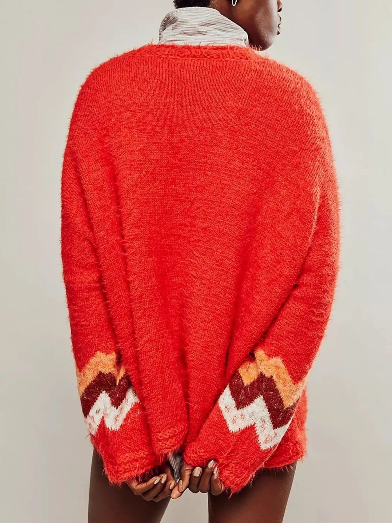 Red sweater with patterned cuffs worn by a person on a plain background