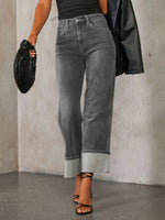 Person wearing gray jeans and a black top against a neutral background