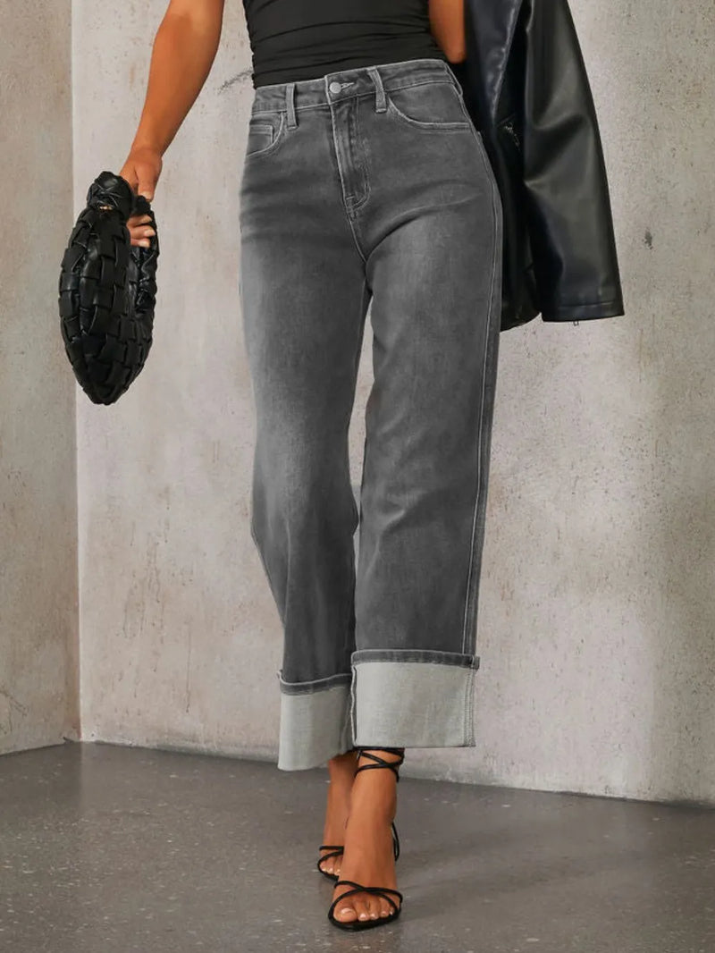 Person wearing gray jeans and a black top against a neutral background