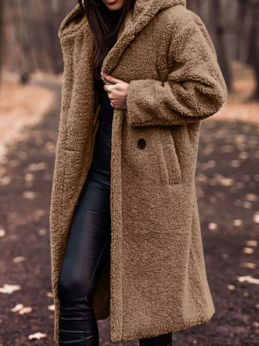 Person wearing a brown teddy coat in a forest setting