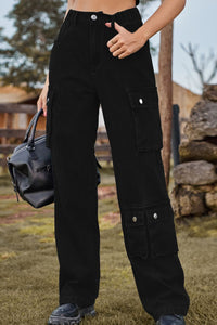 Person wearing black cargo pants holding a black bag outdoors.