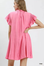 Woman wearing a pink dress with ruffled sleeves on a white background