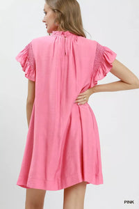 Woman wearing a pink dress with ruffled sleeves on a white background