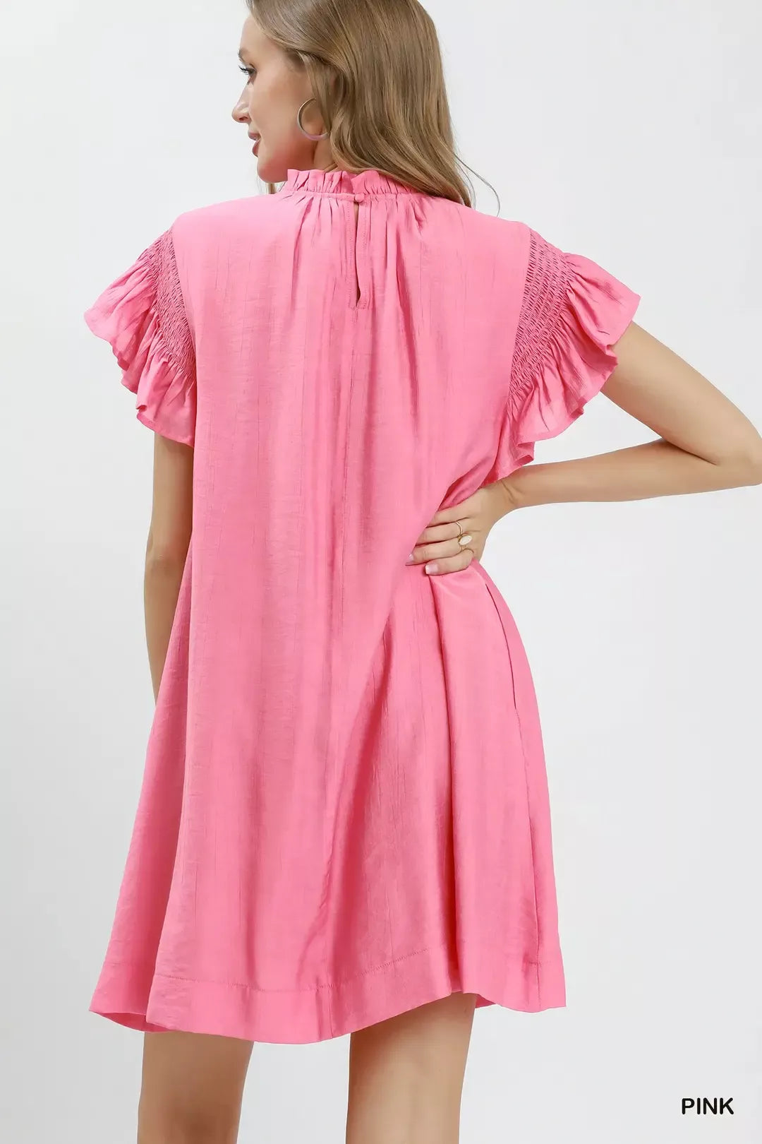 Woman wearing a pink dress with ruffled sleeves on a white background