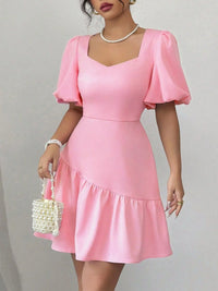 Woman wearing a pink dress with puff sleeves against a gray background