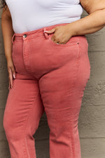 Person wearing pink pants with a white top against a textured wall.