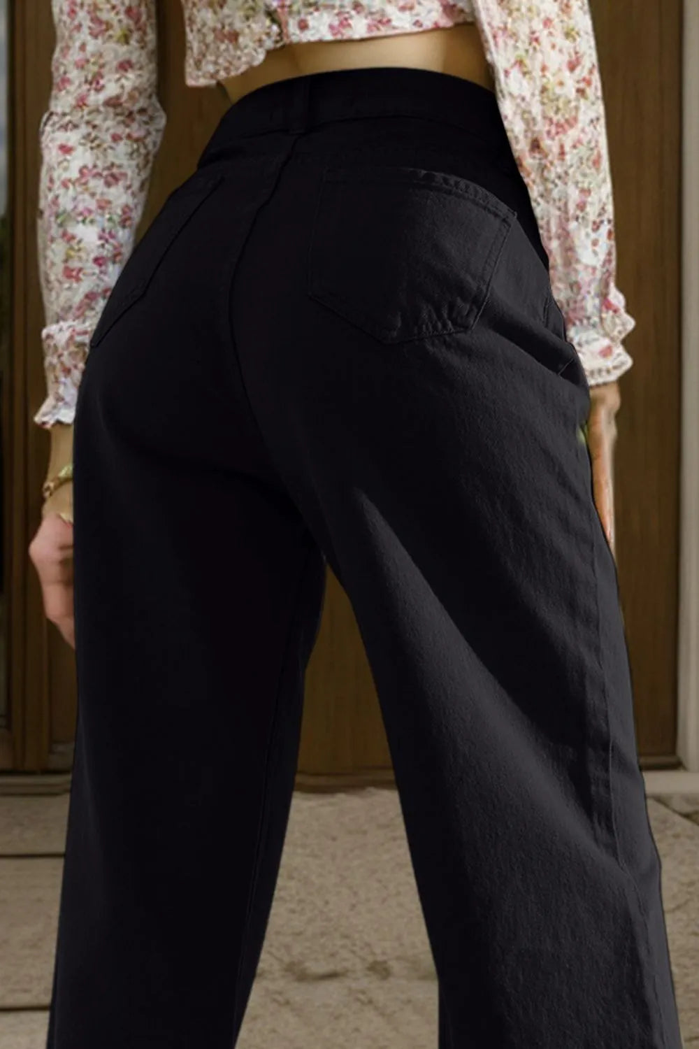 Person wearing black pants with a floral blouse in the background