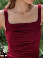 Red sleeveless top worn by a person with a blurred green background
