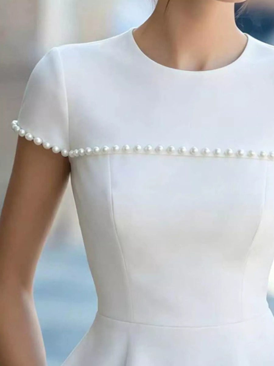 White dress with pearl details on a blurred background
