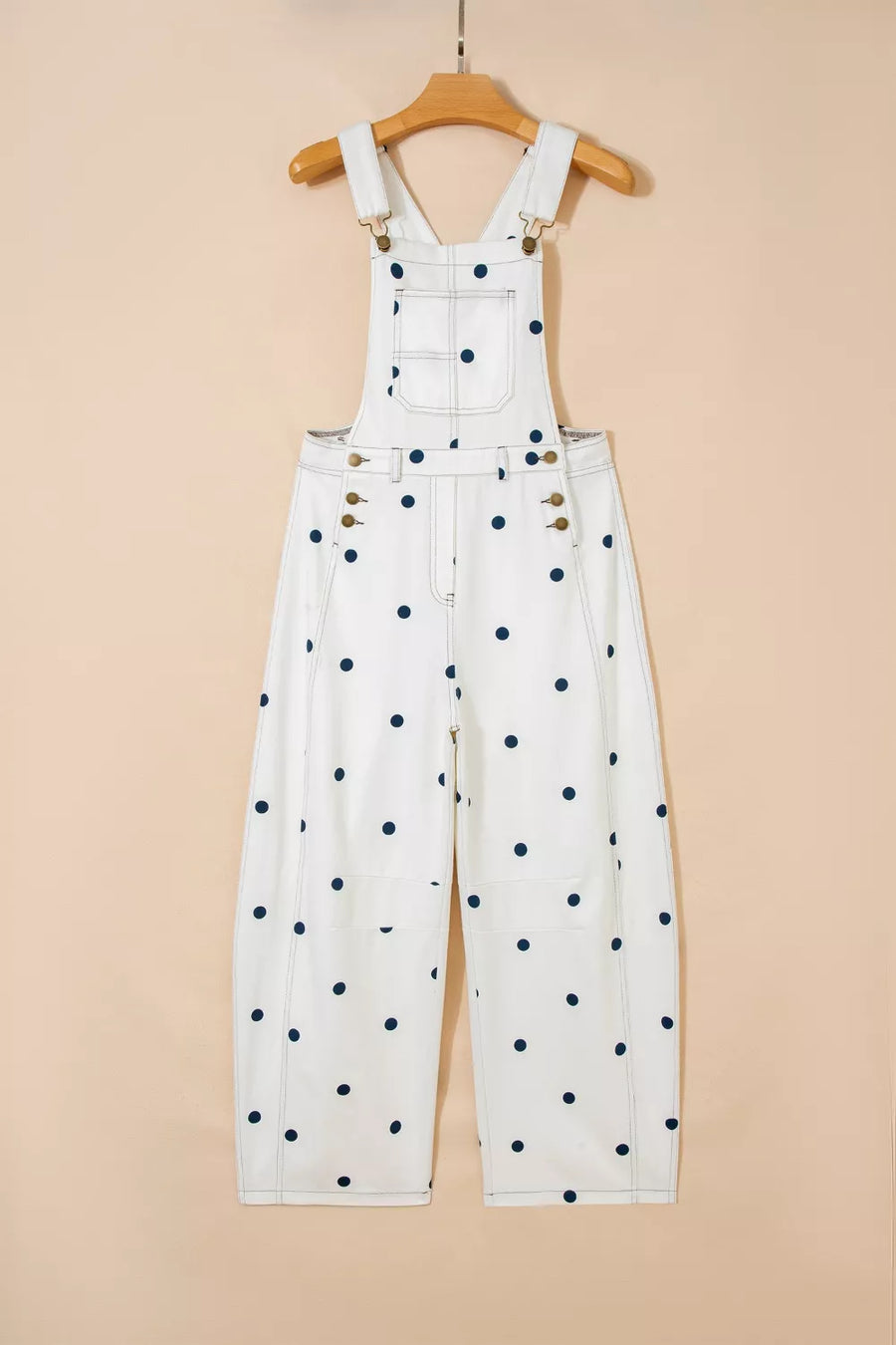 White denim overalls with black polka dots on a beige background