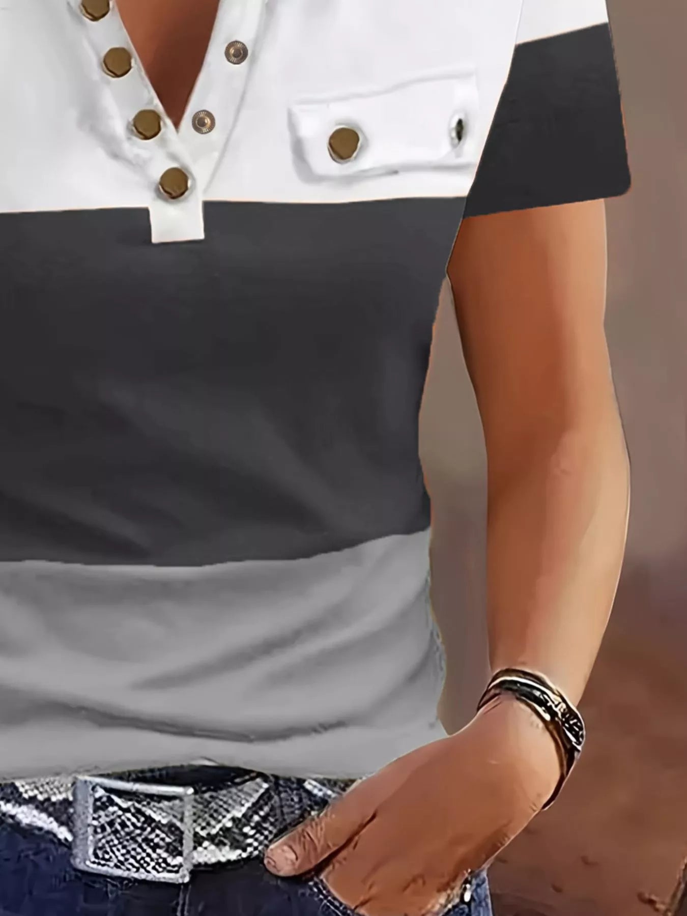 Close-up of a person wearing a black and white top with buttons, blurred background