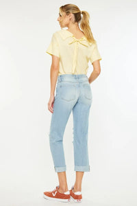 Woman wearing a yellow blouse and light blue jeans on a white background