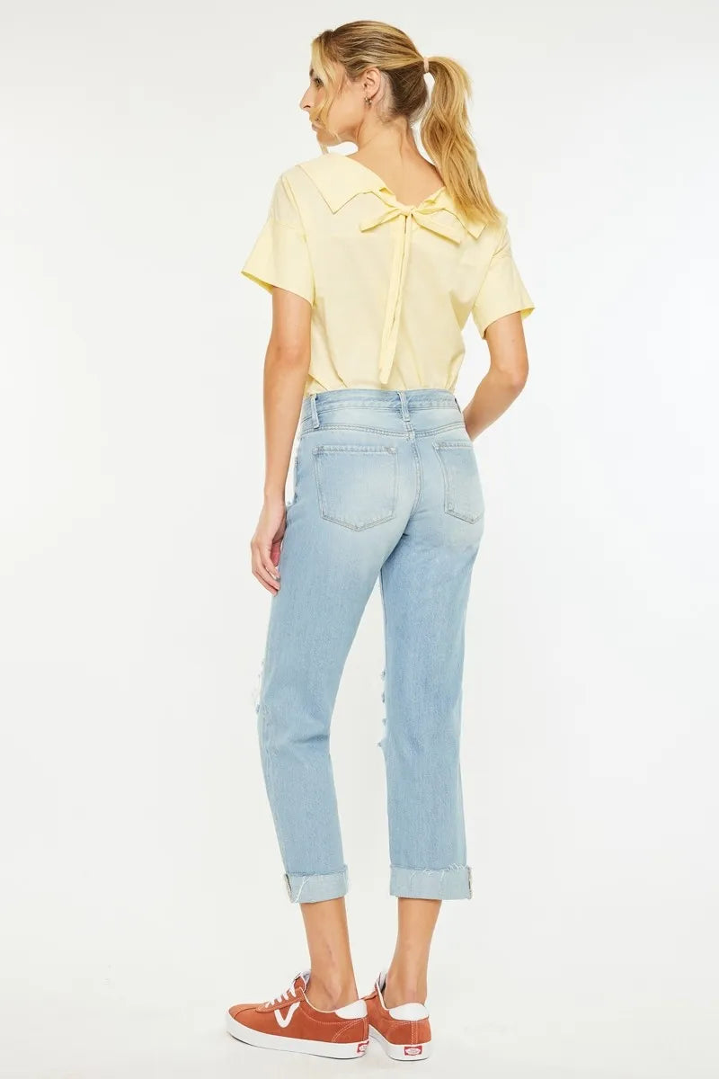 Woman wearing a yellow blouse and light blue jeans on a white background