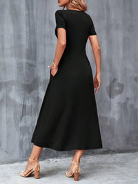 Woman wearing a black dress against a gray concrete wall.