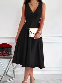 Woman wearing a black dress holding a gold clutch against a white background