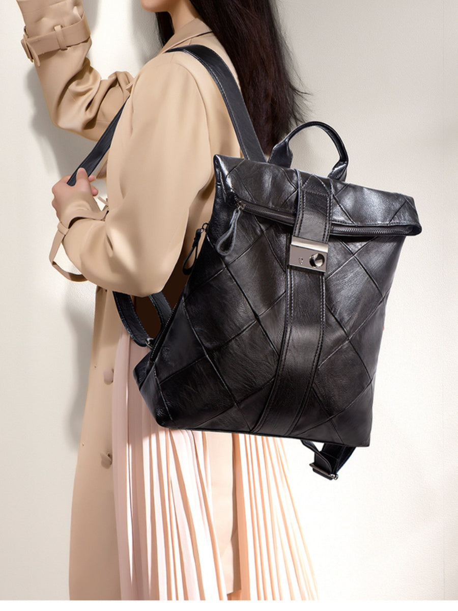 Black woven backpack worn by a person in a beige coat against a neutral background