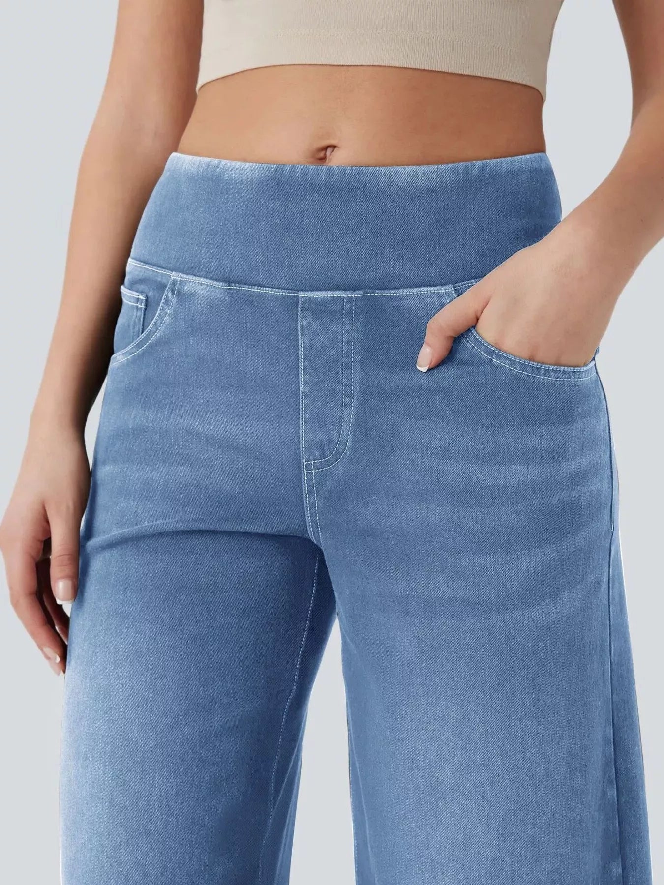 Blue jeans worn by a person on a plain background