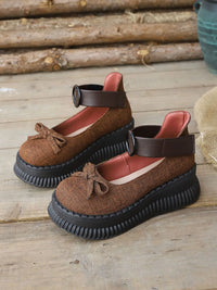 Brown sandals with black soles on a wooden surface