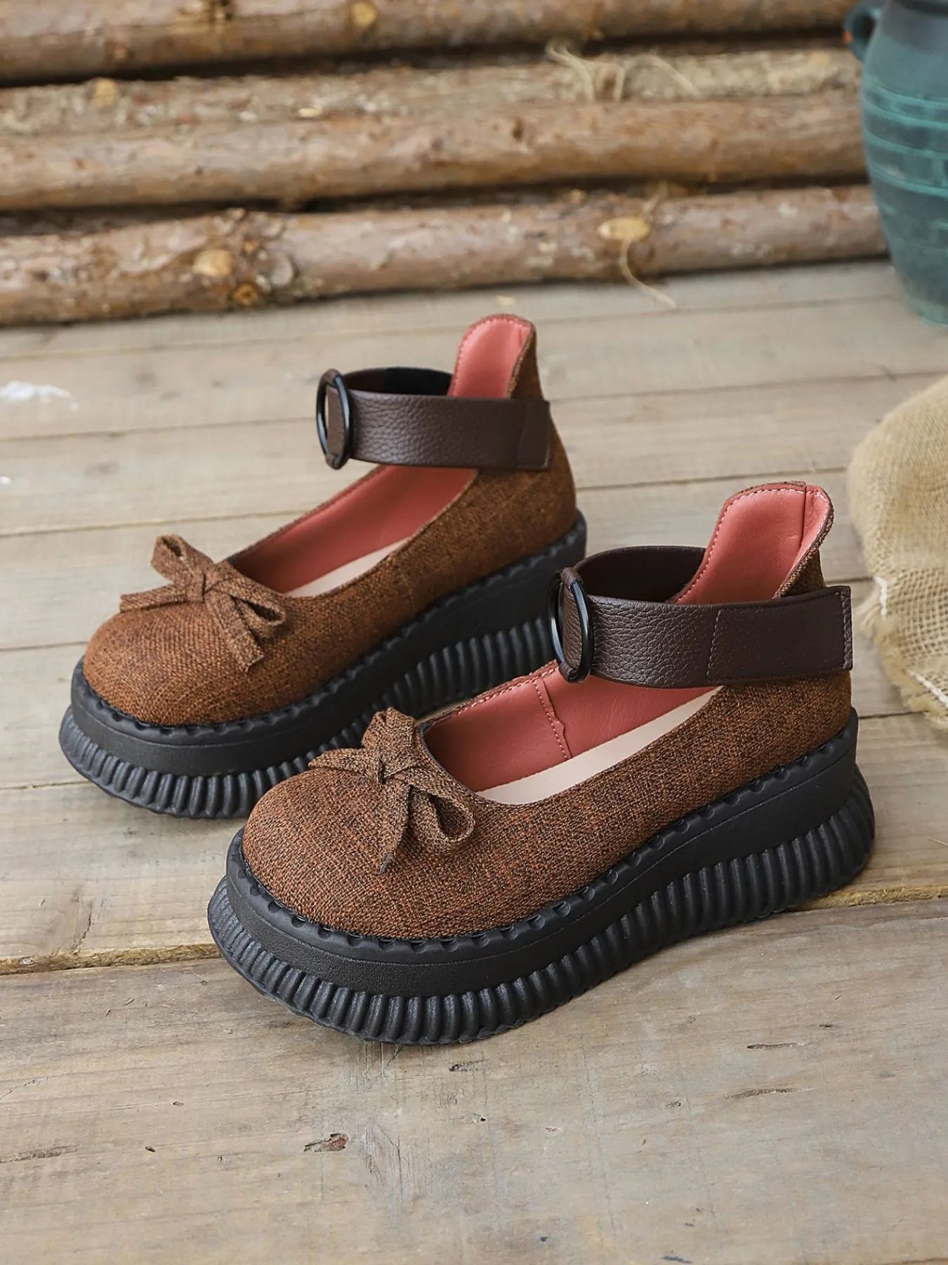 Brown sandals with black soles on a wooden surface