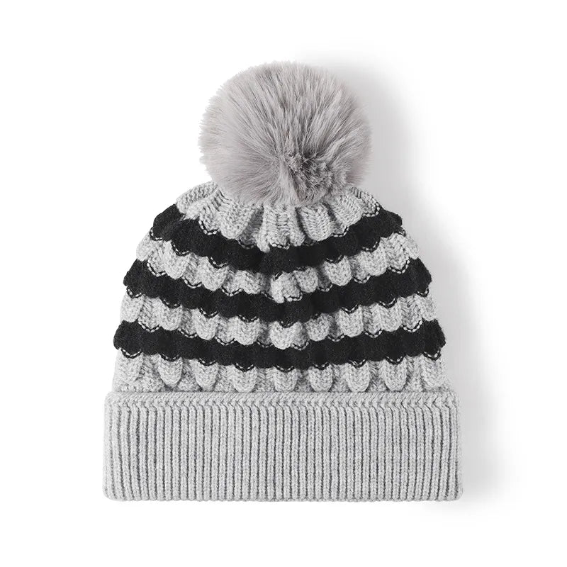 Knitted beanie with black and white striped pattern and gray pom-pom on a white background