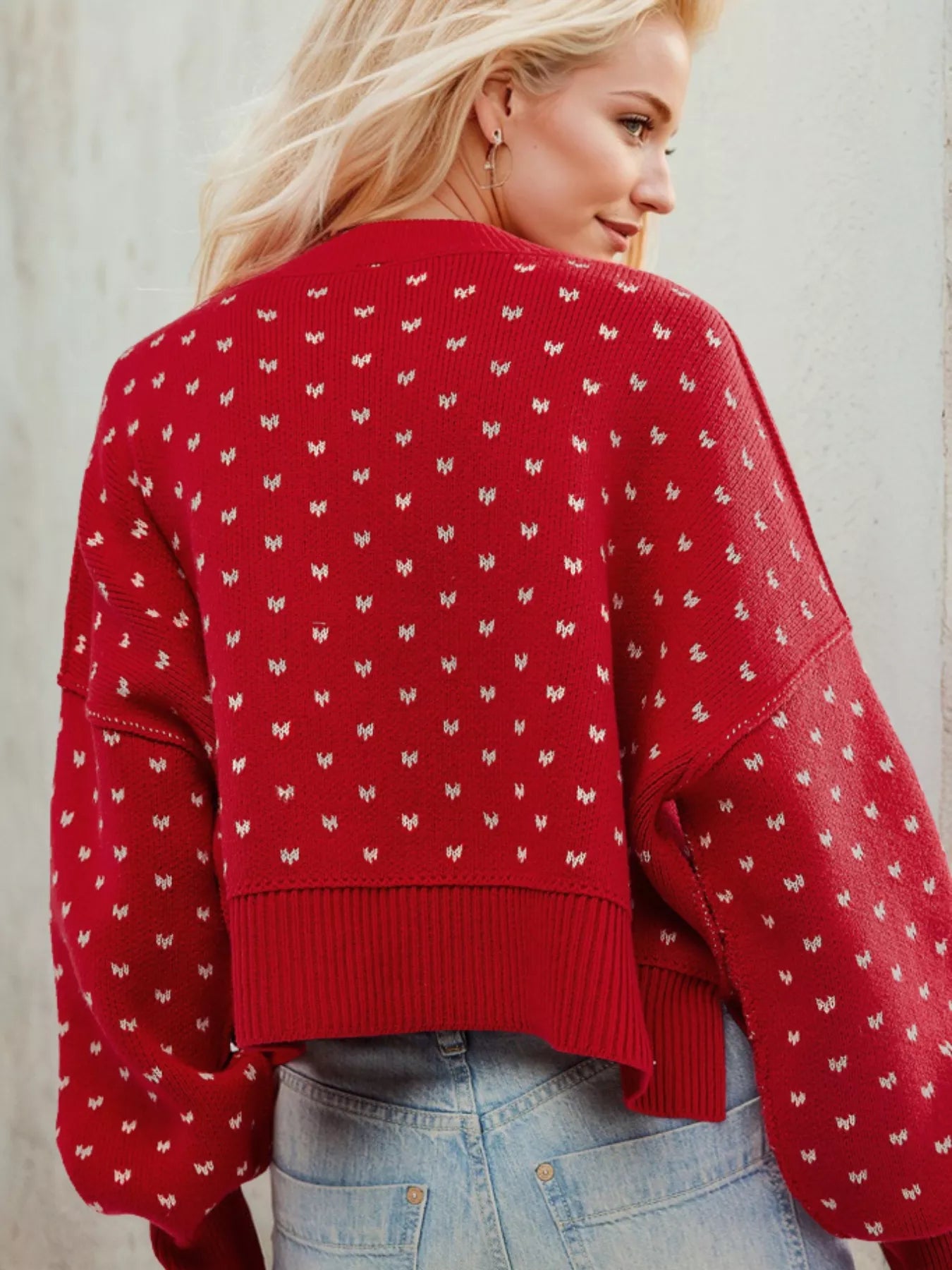Woman wearing a red sweater with white patterns against a light background