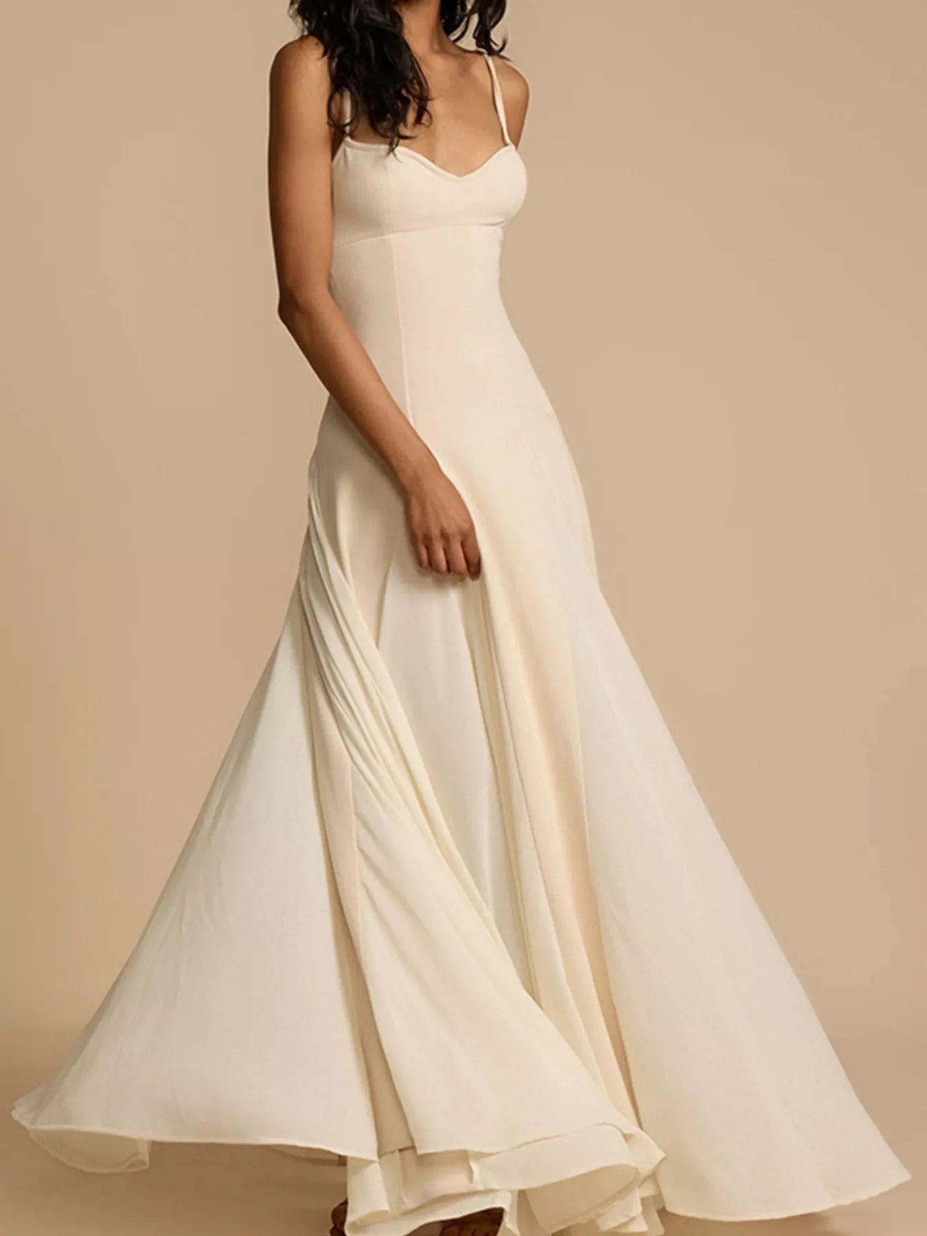 Woman wearing a flowing white dress against a beige background