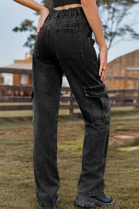 Person wearing black cargo pants in an outdoor setting with a wooden fence and grass.