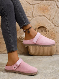 Person wearing pink slippers with a stone wall background
