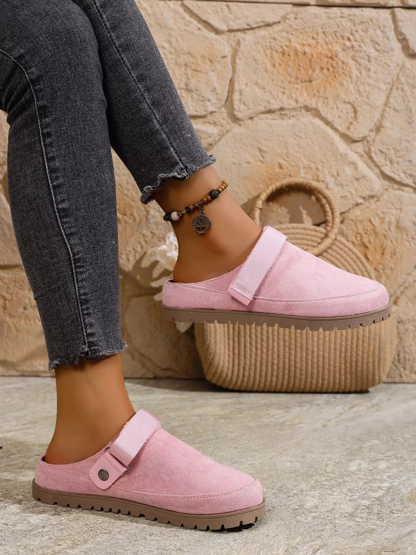Person wearing pink slippers with a stone wall background