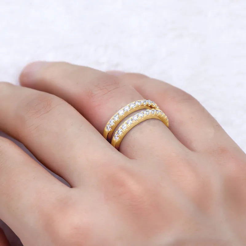 Gold ring with diamonds on a person's finger against a white background