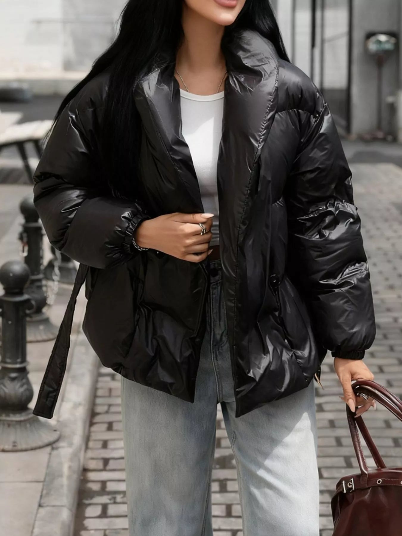 Person wearing a black puffer jacket on a city street.
