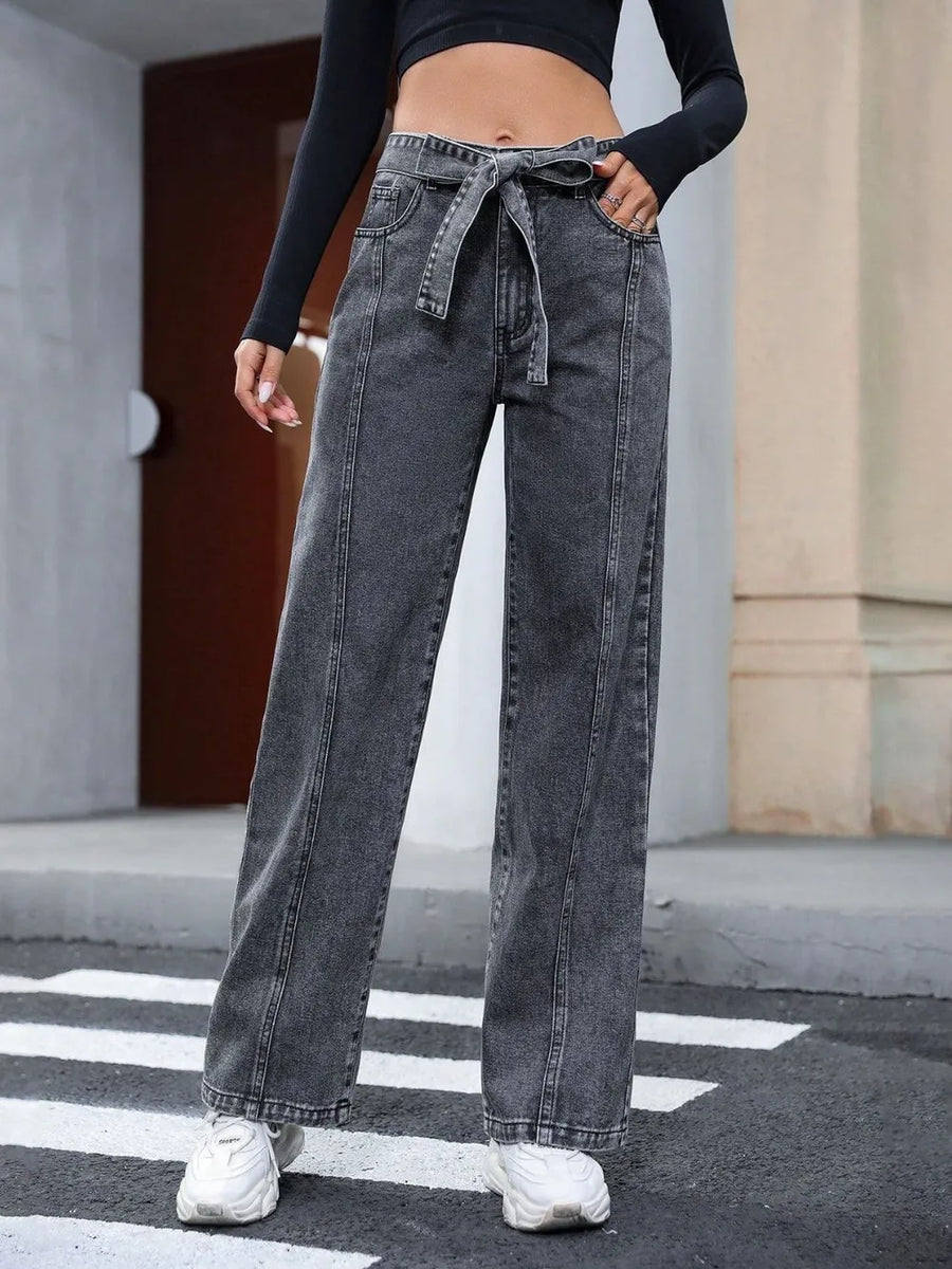 Person wearing high-waisted black jeans on a city street.