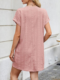 Woman wearing a pink textured dress against a white wall.
