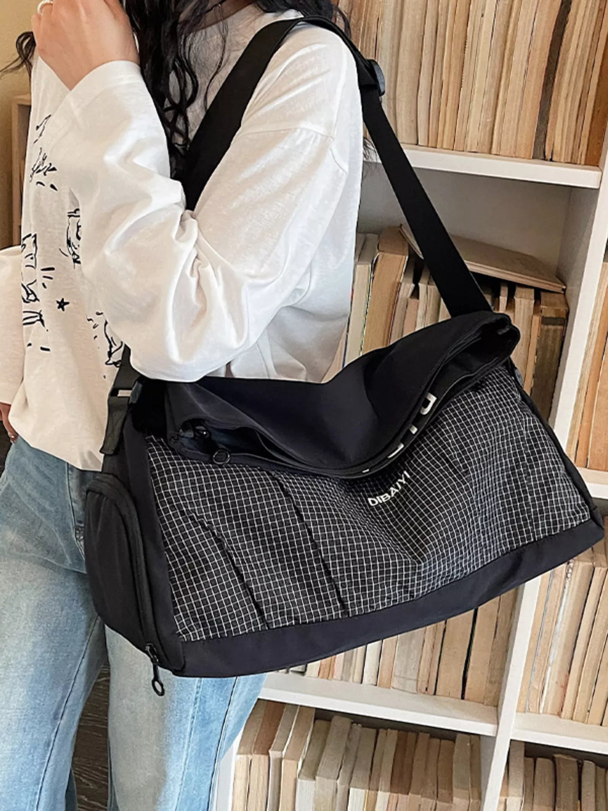 Person holding a black and gray checkered bag in front of a bookshelf