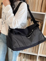 Person holding a black and gray checkered bag in front of a bookshelf