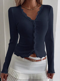 Navy blue long-sleeve top with scalloped neckline worn by a person on a plain background